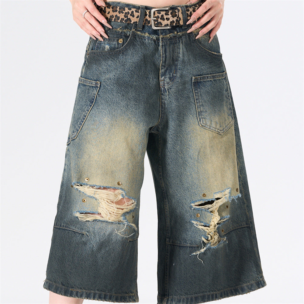 Men's wide-leg ripped distressed denim shorts in washed blue with cargo pockets and brass rivet details, front and back view