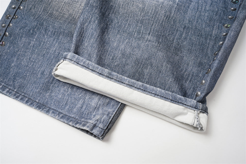 Jean large homme déchiré avec empiècement camouflage, clous et ceinture