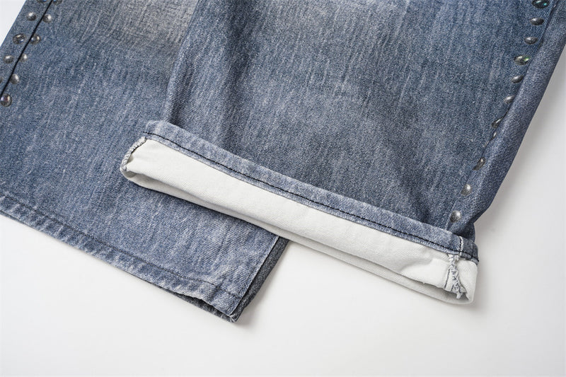 Jean large homme déchiré avec empiècement camouflage, clous et ceinture