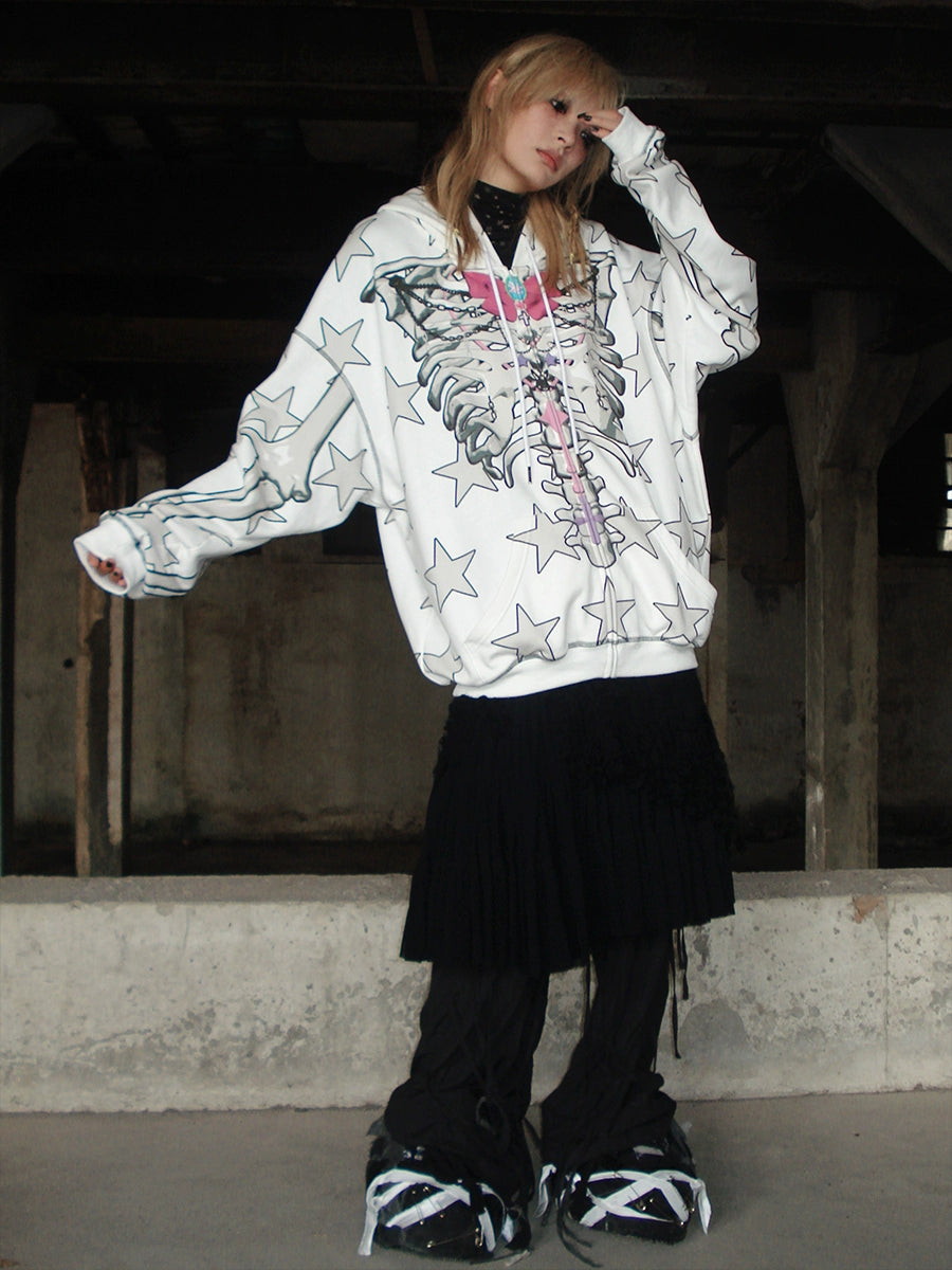 In an industrial setting, someone poses in a Seakoff Gothic Skeleton Star Hoodie, featuring a skeleton and star print. It pairs perfectly with a black skirt and chunky shoes, capturing the alternative fashion vibe as they bend one arm while gripping the hoodie collar with the other.