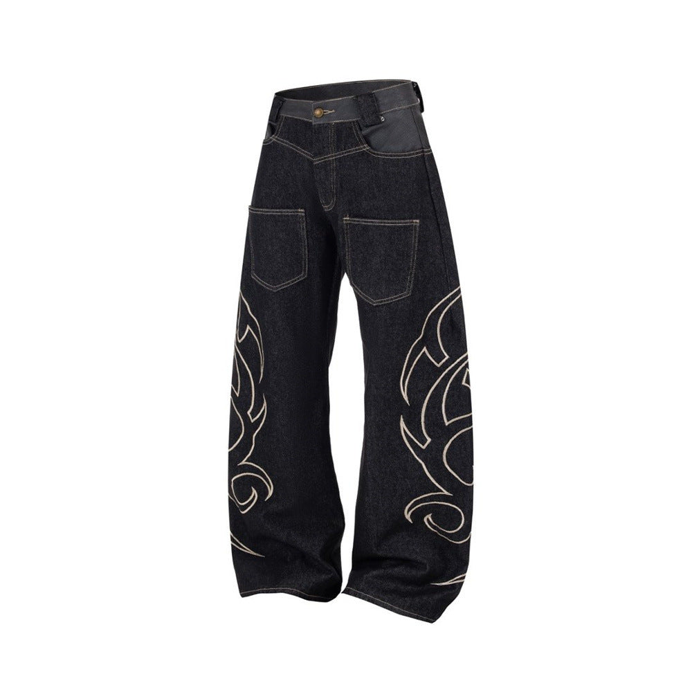 Angled front view of black baggy jeans with embroidered flame pattern on the legs