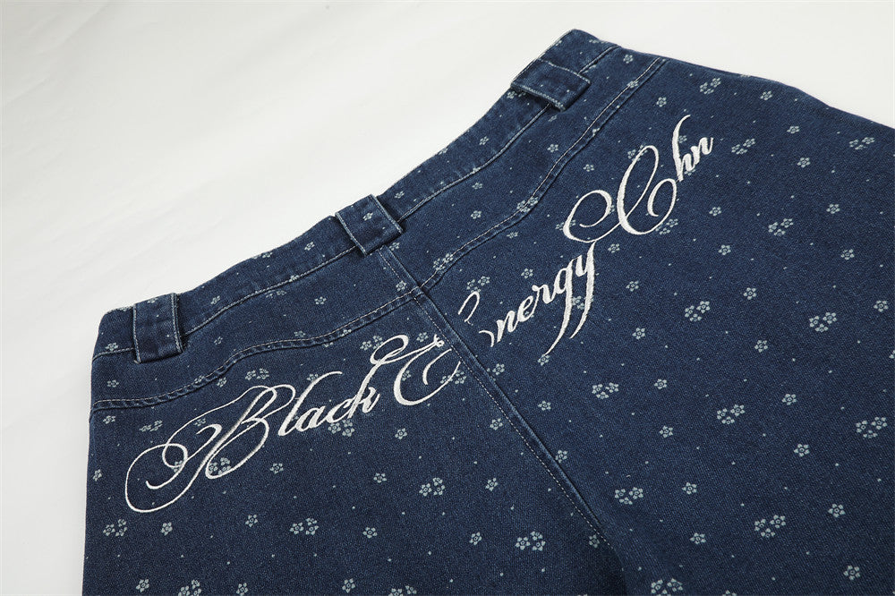 Close-up of back waist of dark blue jeans with white script embroidery