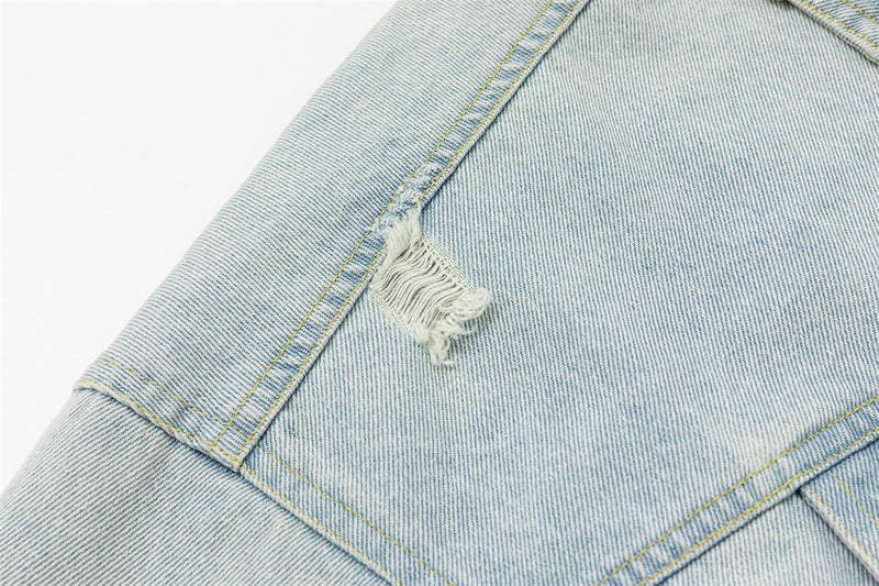 Close-up of a frayed distressed patch on the light wash denim jacket shoulder