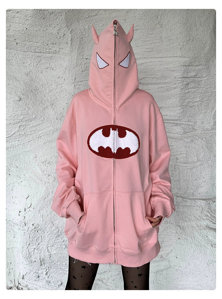 A person is wearing a Seakoff Batman-Inspired Hoodie, an oversized pink zip-up with pointed ears and a stylized bat emblem, paired with star-patterned tights.