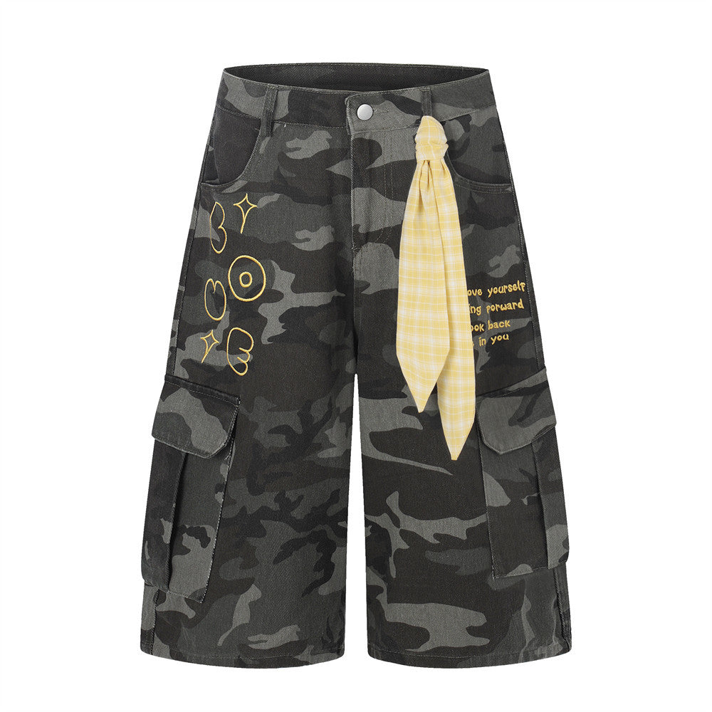Men's wide-leg dark grey camouflage cargo shorts with yellow plaid bandana tied at waist and gold embroidered text detail
