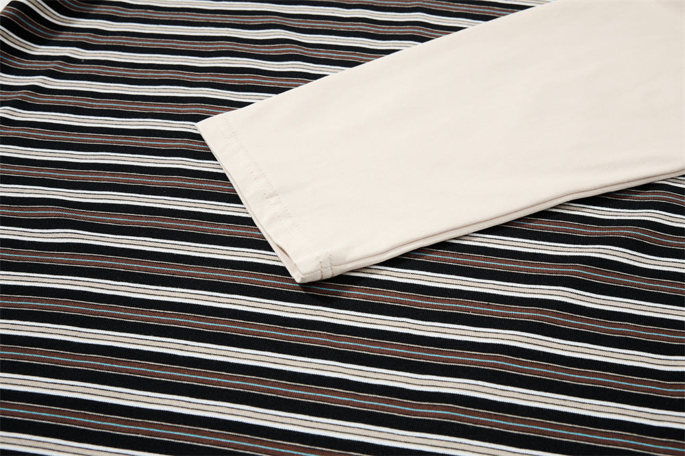Close-up of cream long sleeve laid over black striped fabric