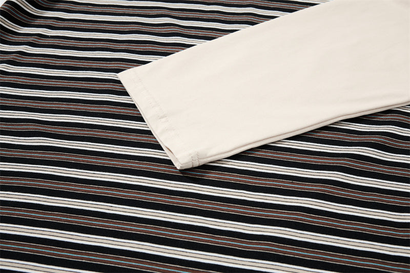 Close-up of cream long sleeve laid over black striped fabric