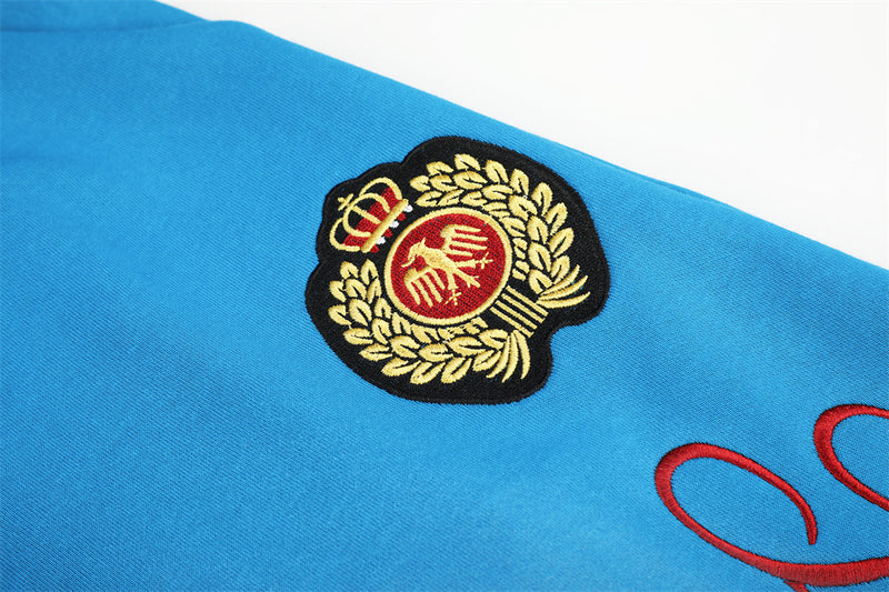 Close-up of embroidered crest badge on blue sweatpants
