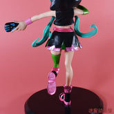 The Hatsune Miku Cat Hoodie 17cm PVC Figure features an anime-style character with teal hair, wearing a black and pink outfit with green accents and a cat hoodie, holding a gaming controller. She stands on a round black base against a pink background.