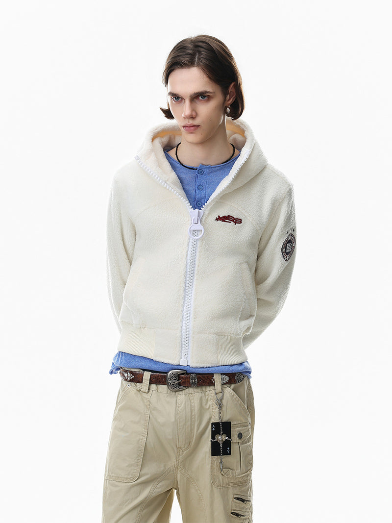 Cream sherpa fleece zip-up hoodie jacket with embroidered chest logo and varsity badge patch, styled with cargo pants