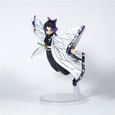 The Demon Slayer Shinobu Kocho Action Figure features black hair with purple highlights, dressed in a chic white and black outfit with butterfly wing-like sleeves. With its dynamic pose on a clear stand gripping a small sword, it&