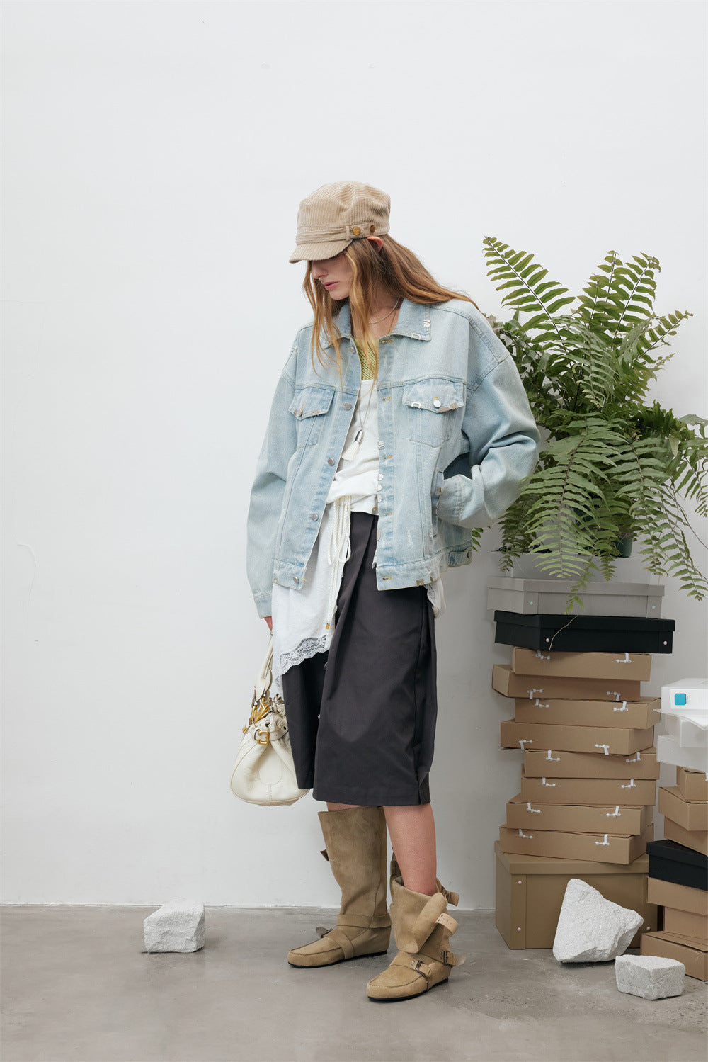 Side view of a model wearing a light wash denim jacket with distressed details and metal hardware