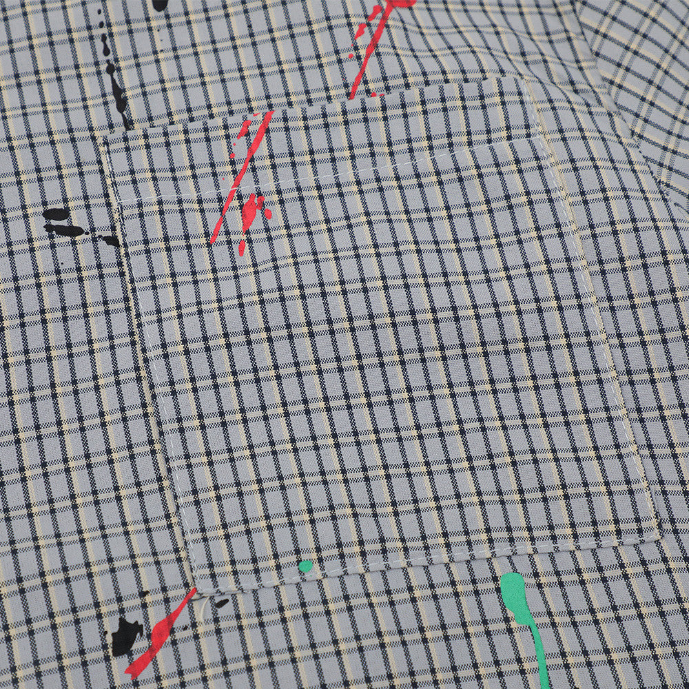 Close-up of front chest pocket on gray plaid shirt with red and teal paint splatter