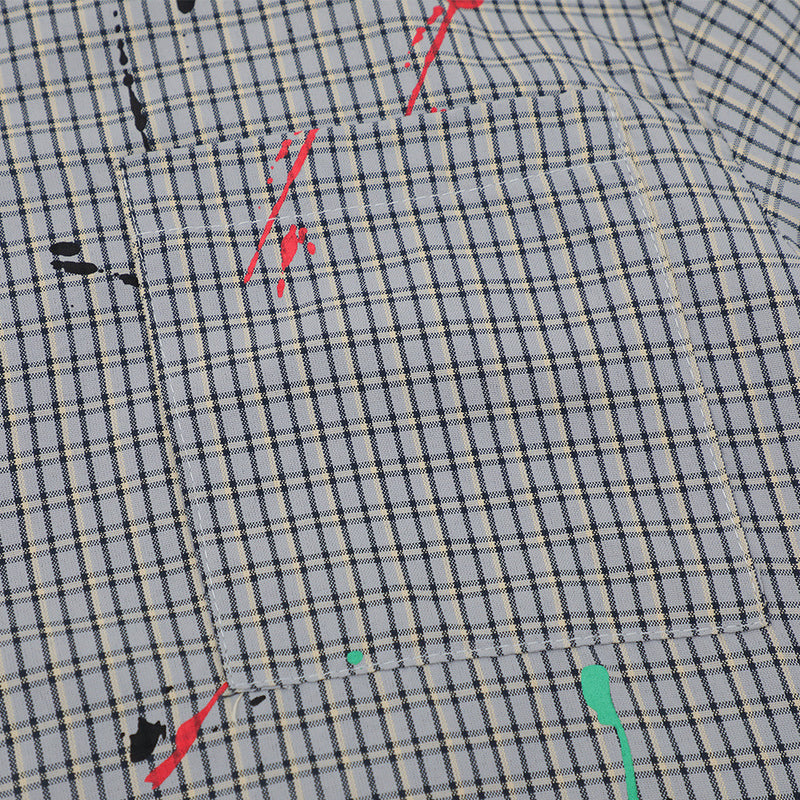 Close-up of front chest pocket on gray plaid shirt with red and teal paint splatter