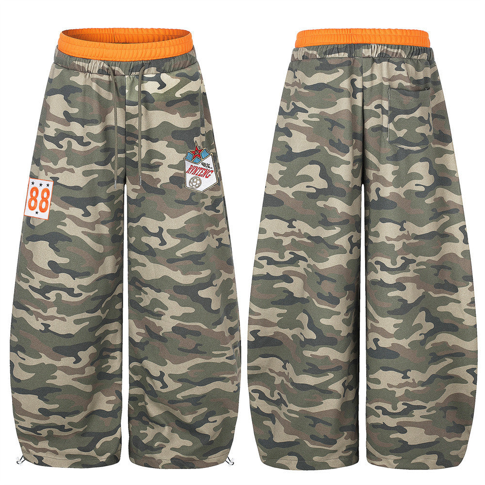 Oversized camouflage wide-leg sweatpants with orange contrast waistband, embroidered sport patches, and cinched ankle hem, fr