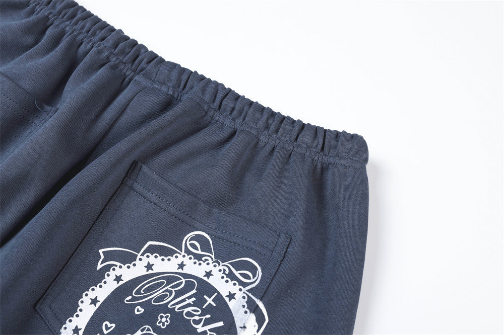 Close-up of navy track pants back pocket area with white printed graphic detail