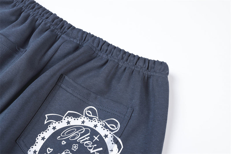 Close-up of navy track pants back pocket area with white printed graphic detail