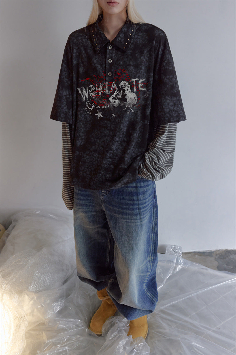 Model wearing a dark mottled polo shirt with striped long sleeves, collared neckline, and front graphic