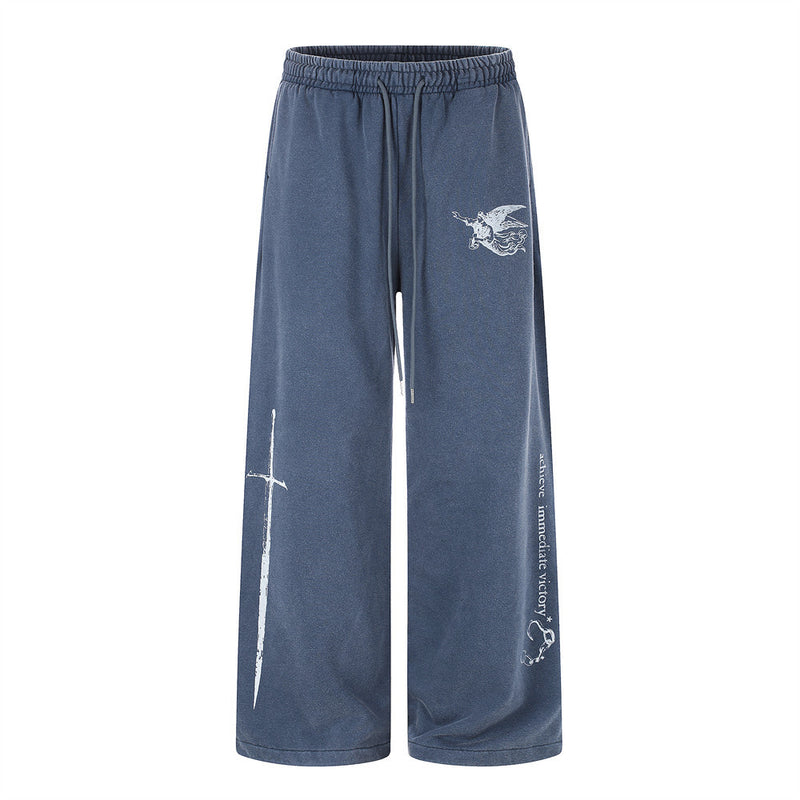 Wide-leg sweatpants in washed blue with angel figure, sword graphic, and 'achieve immediate victory' slogan print on the leg