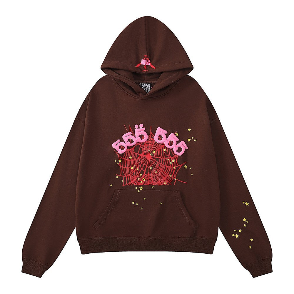 The Sp5der “555 Web” Hoodie is a brown/pink oversized streetwear pullover made from 440GSM heavyweight cotton fleece, featuring a red spider web and pink 555 text on the front, yellow star details on the sleeves, and a hood with a red spider graphic.