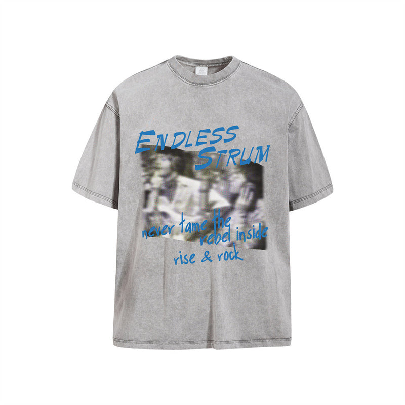 オーバーサイズのアシッドウォッシュ加工グラフィックTシャツ。胸元に「Endless Strum」のハーフトーン人物プリントとブルーのロゴ入り