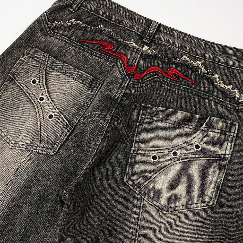 Back view close-up of faded denim pockets with metal eyelets and red embroidered yoke