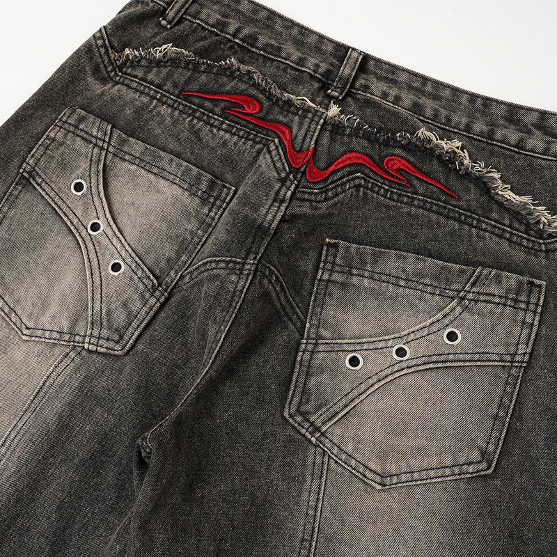 Back view close-up of faded denim pockets with metal eyelets and red embroidered yoke