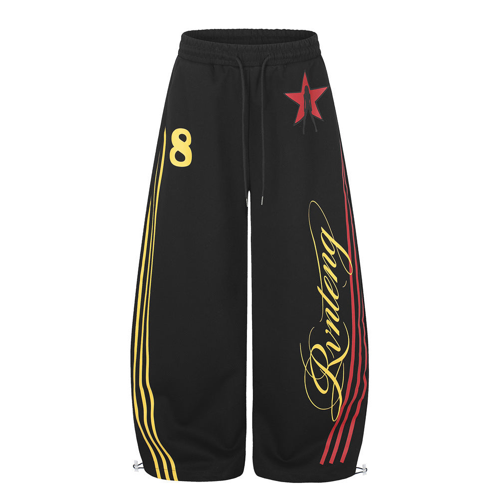 Schwarze Wide-Leg-Sweatpants mit rotem Sternmotiv, dreifachen Seitenstreifen in Gelb und Rot sowie kursivem Schriftlogo am Bein