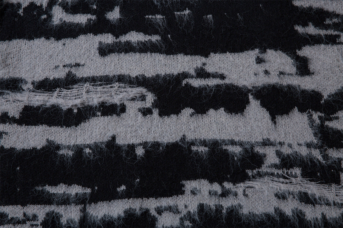 Detailed view of irregular black and gray horizontal stripes across the distressed knit sweater fabric