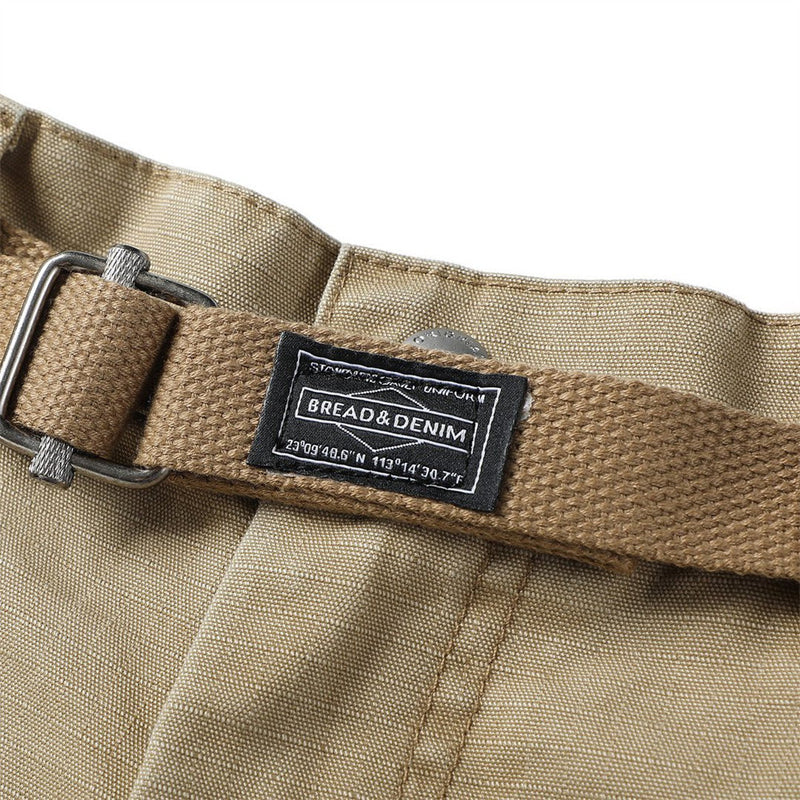 Close-up of khaki woven belt and branded waist label on cargo shorts