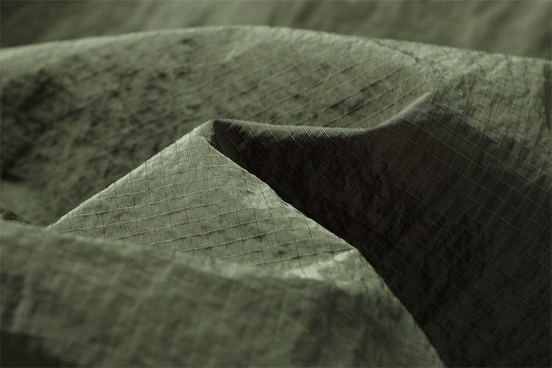 Macro view of the crinkled woven texture of olive parachute pants fabric