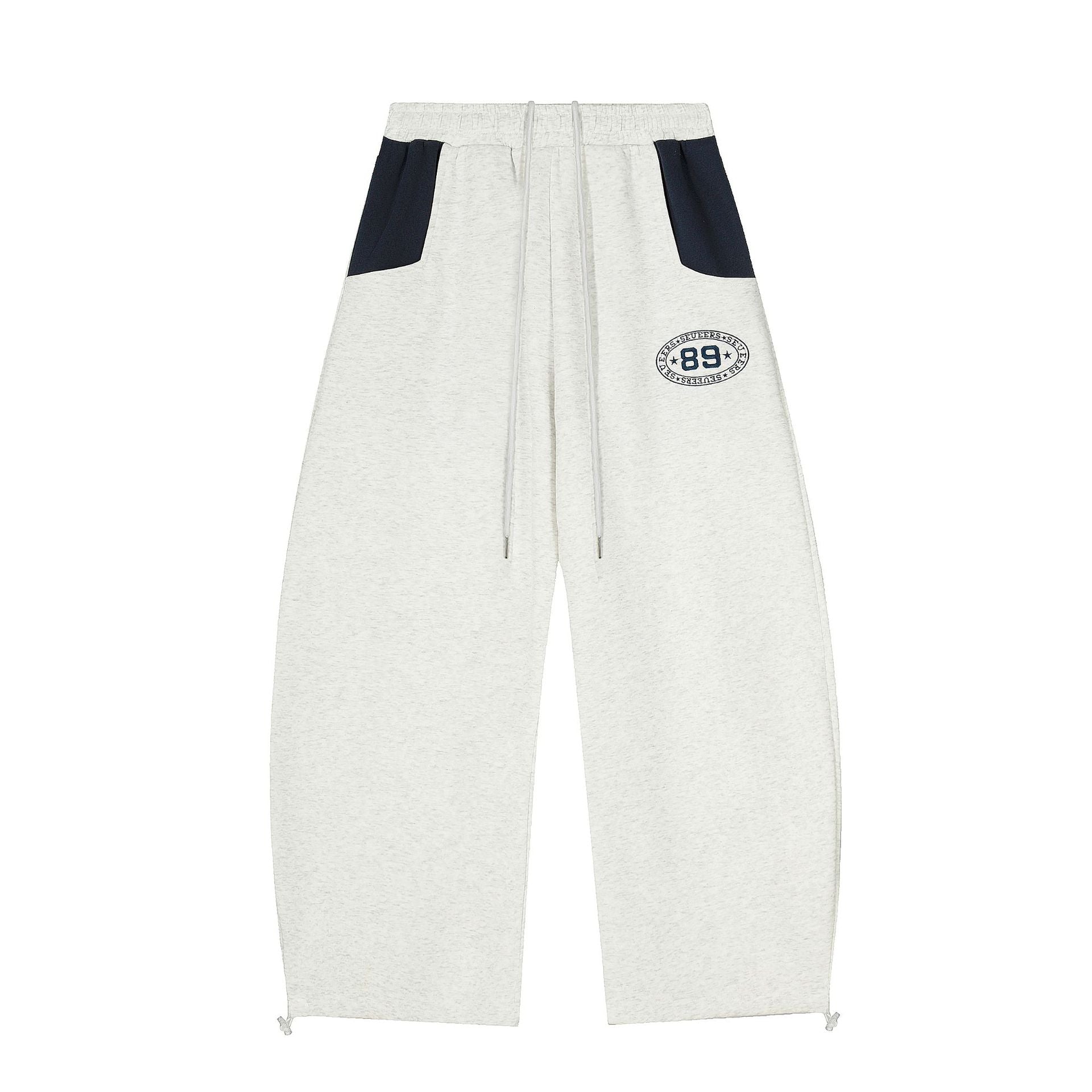 Wide-leg colorblock sweatpants in light heather grey with navy contrast pockets and embroidered varsity 89 badge on the thigh