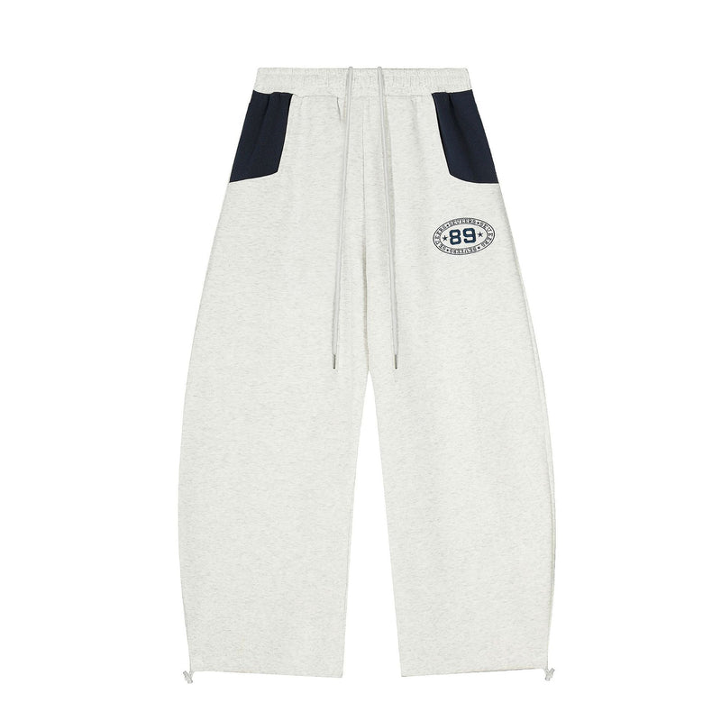 Wide-leg colorblock sweatpants in light heather grey with navy contrast pockets and embroidered varsity 89 badge on the thigh