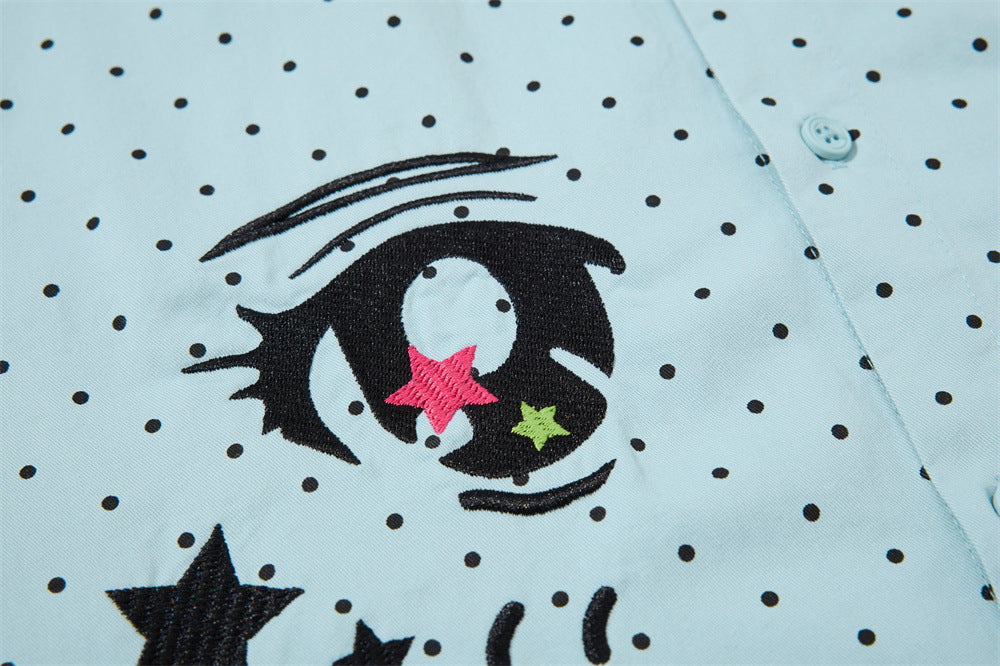 Close-up of the left embroidered eye graphic on the light blue shirt