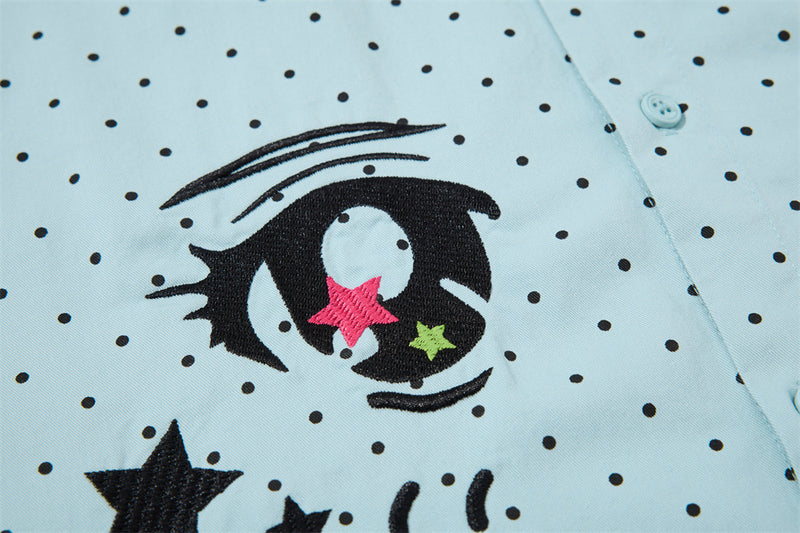 Close-up of the left embroidered eye graphic on the light blue shirt