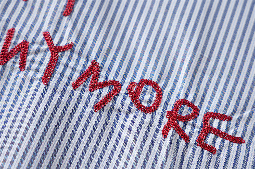 Close-up of red embroidered letter graphic on blue and white striped shirt front