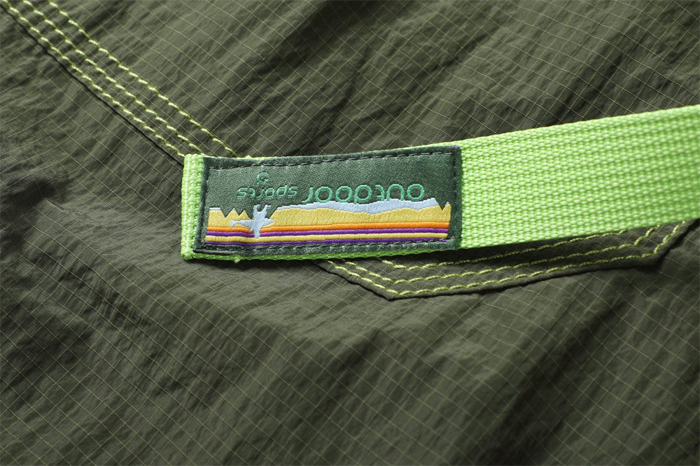 Close-up of a colorful striped fabric label attached to the bright green belt on olive pants
