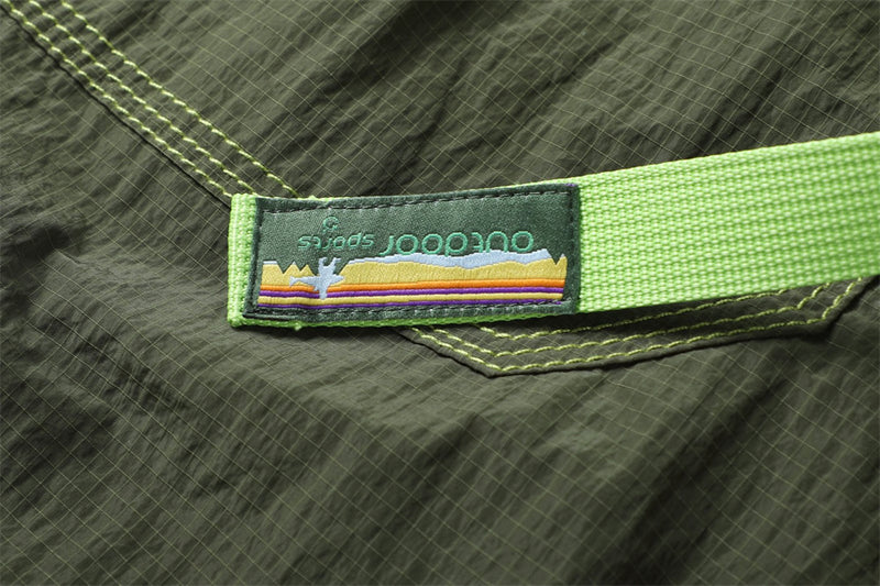 Close-up of a colorful striped fabric label attached to the bright green belt on olive pants