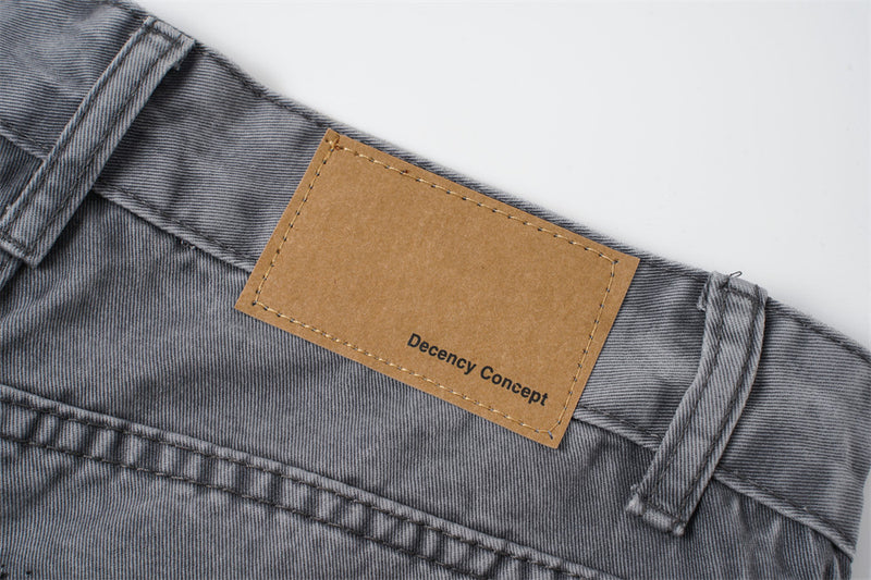Tan waistband patch reading Decency Concept on washed grey jeans