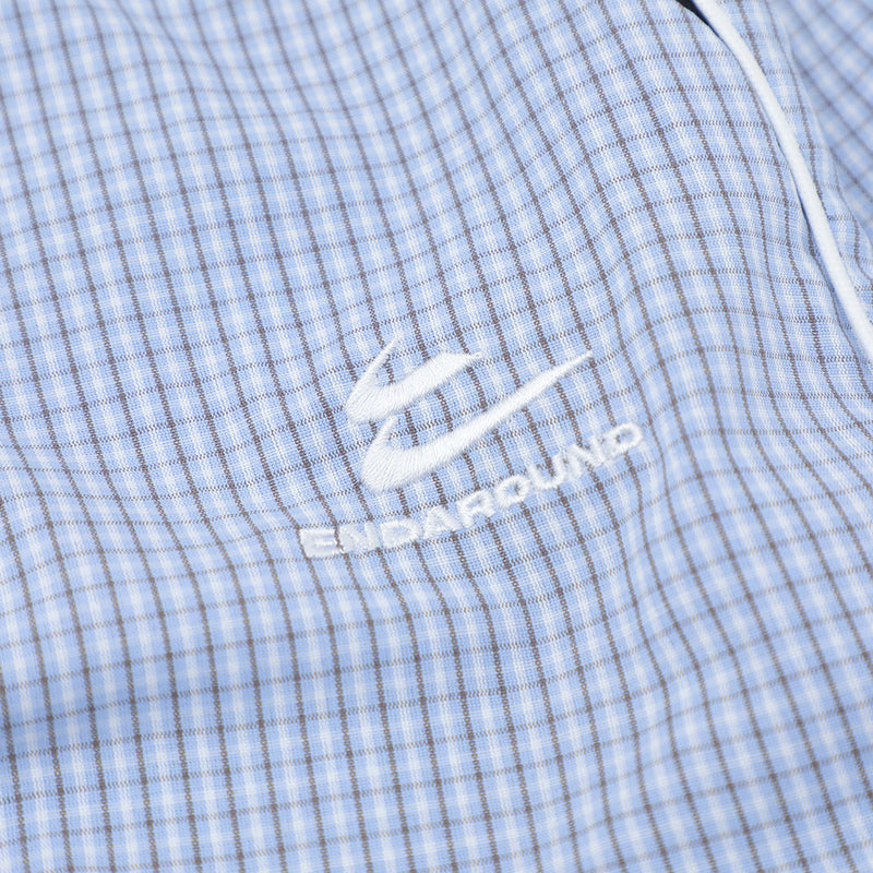 Close-up of embroidered logo on light blue plaid fabric