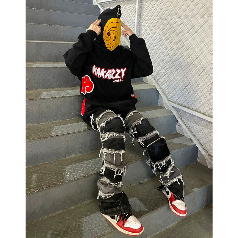 A person on metal stairs wears an Akatsuki spiral mask, a Seakoff Uchiha Obito-inspired hoodie with red and white text, distressed jeans with patches, and black, red, and white high-tops while adjusting their hood—perfect for Naruto fans.