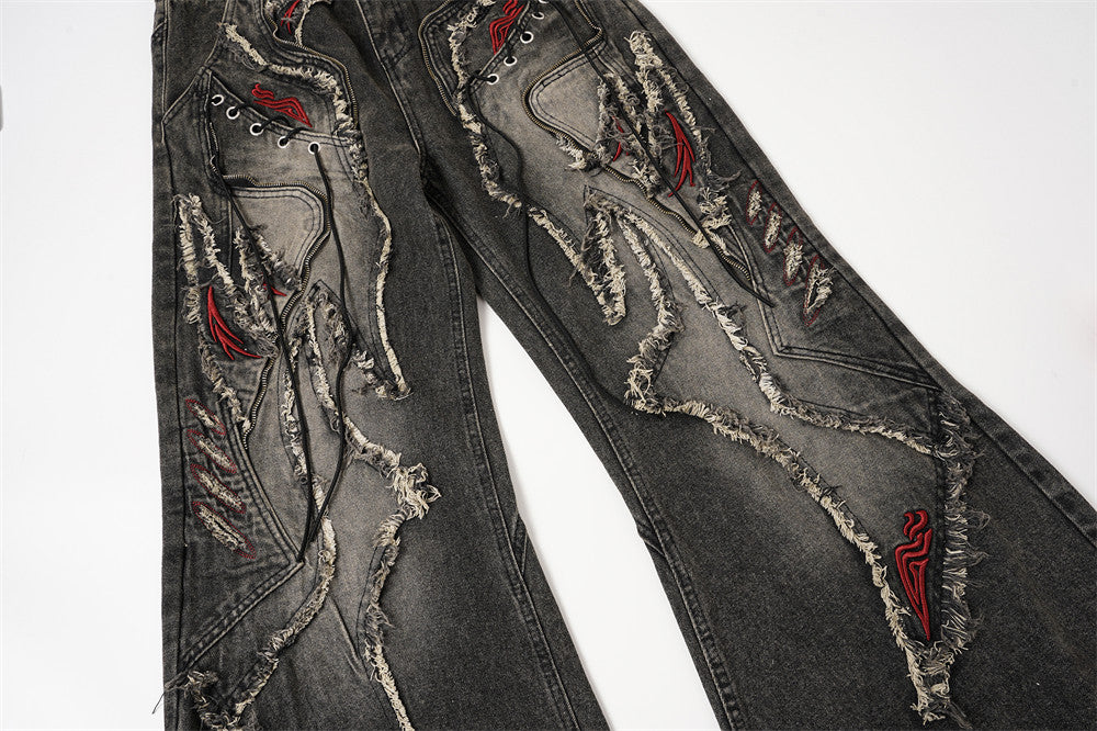 Front view of distressed black flare jeans with raw-edge patchwork and red embroidered details