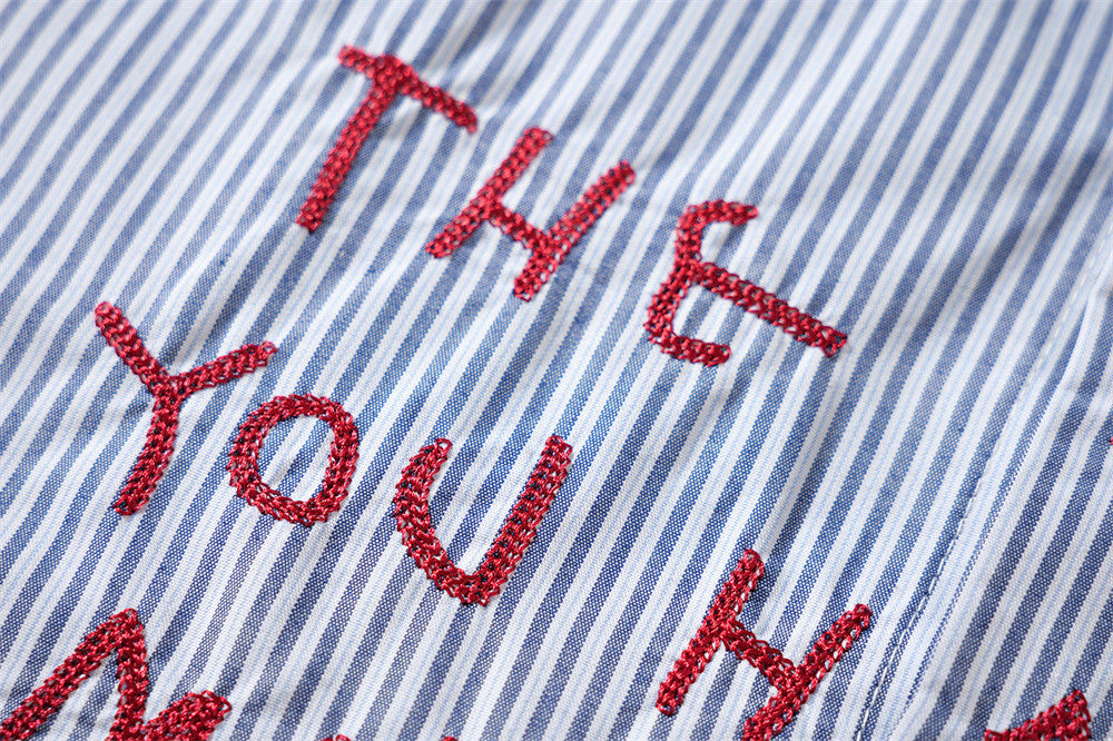 Close-up of red embroidered words on blue striped shirt front