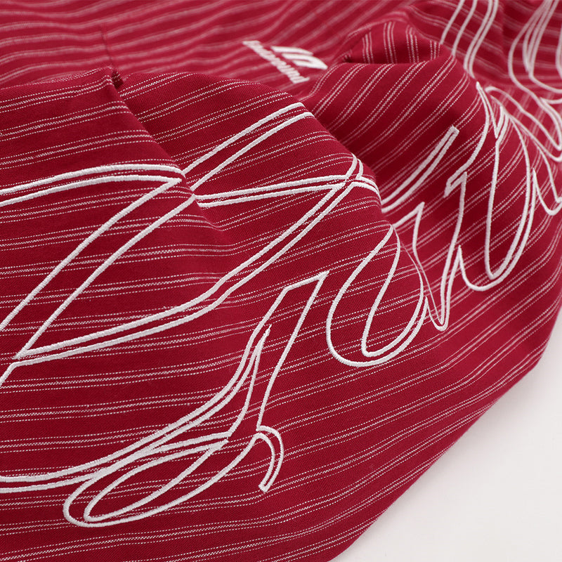 Close-up of white script embroidery on the red striped sleeve