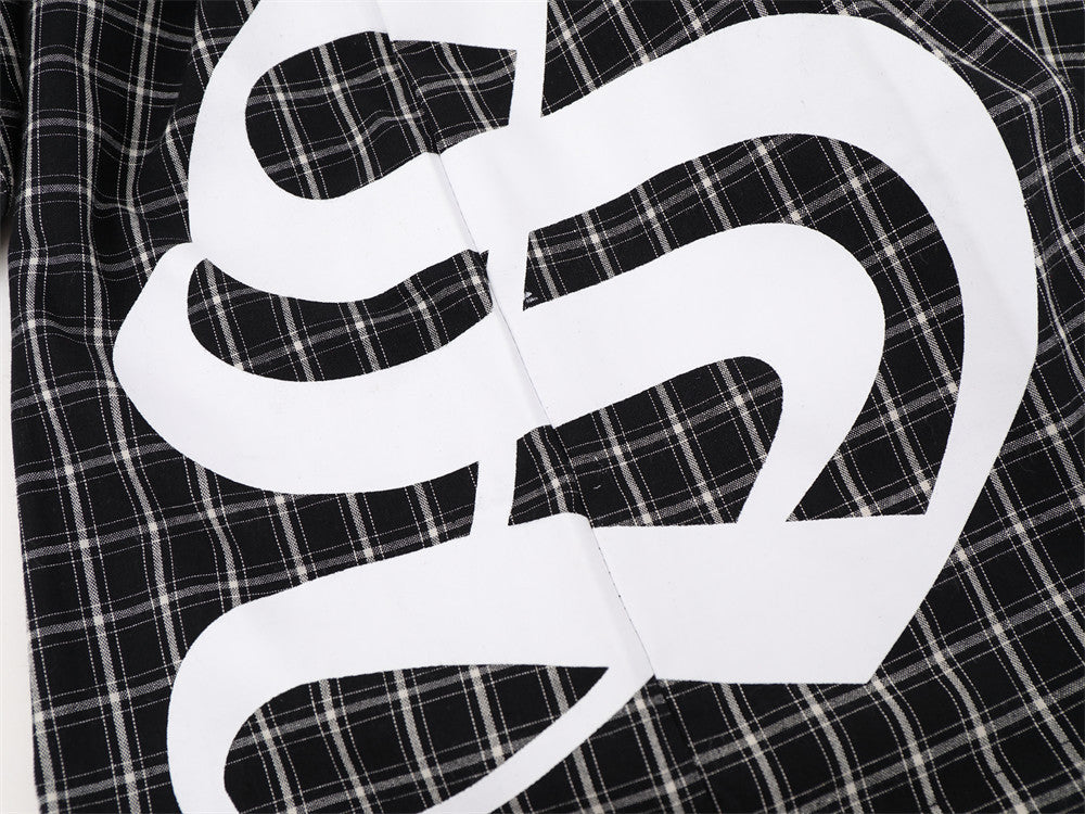 Close-up of large white printed graphic on black plaid shirt