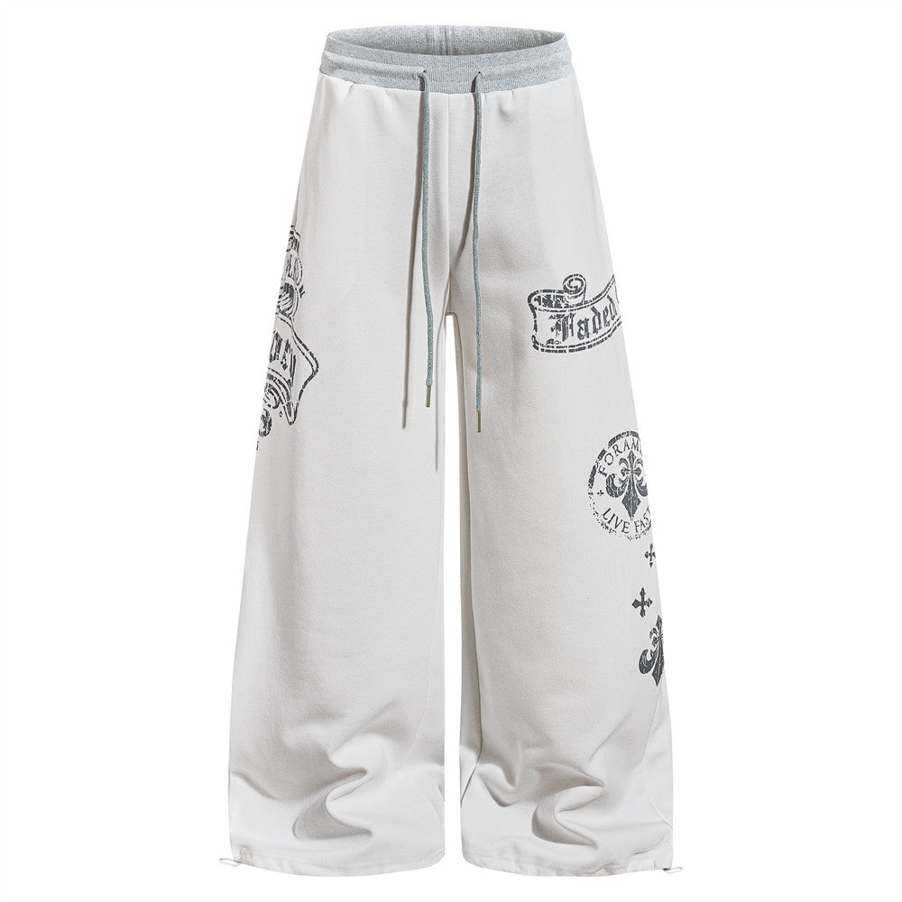 Men's oversized wide-leg sweatpants in white with distressed gothic graphic prints including banner scrolls, cross motifs, an