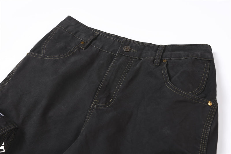 Close-up of black pants waistband with button closure, belt loops, and curved front pockets