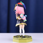 Anya Forger PVC Figure by Spy × Family features an 18 cm elegant design with pink hair and a school uniform, holding a toy unicorn against a blurred dark blue curtain backdrop. She wears black and gold attire with white socks and black shoes.