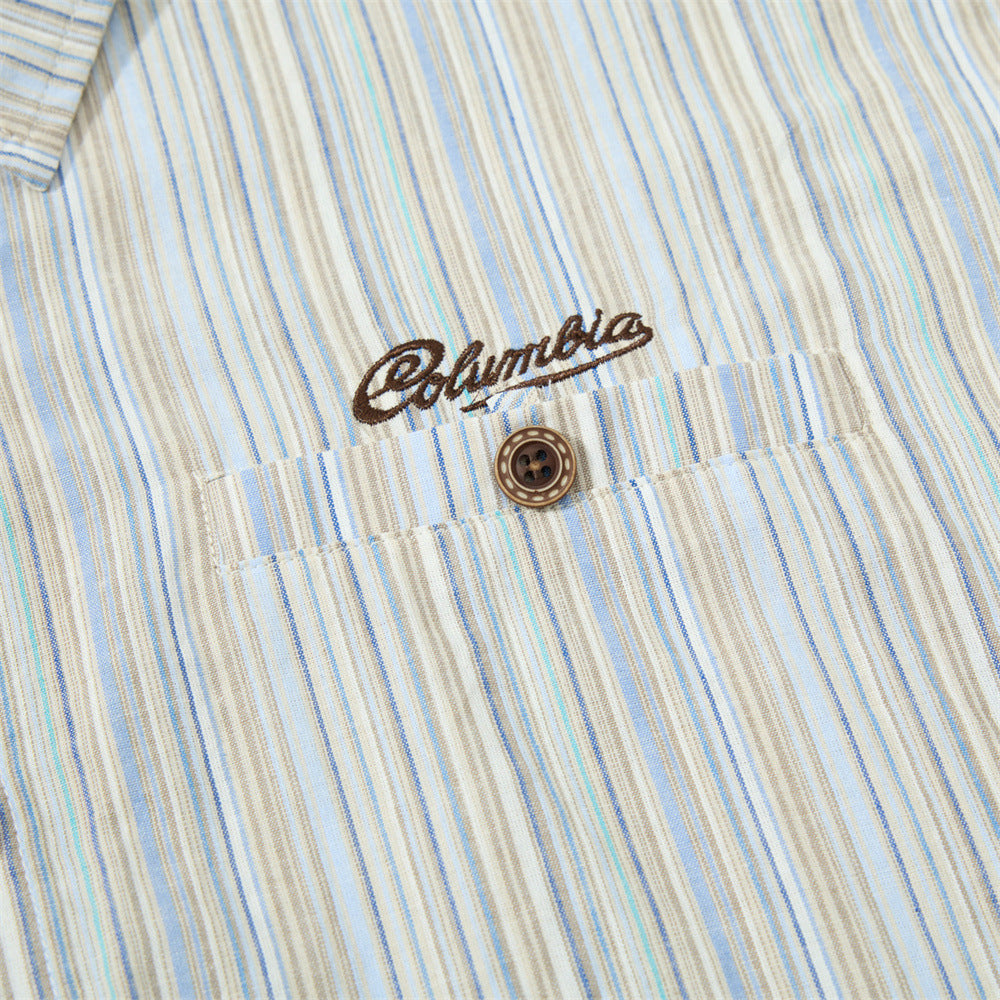 Close-up of embroidered chest logo and top button on striped shirt fabric