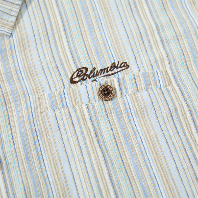 Close-up of embroidered chest logo and top button on striped shirt fabric